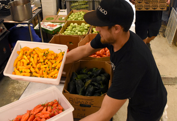 Kit Perreault and Josh Wedel carry in boxes of produce that was grown at The Mad Taco’s farm on Marble Hill Road. Photo: Christopher Keating