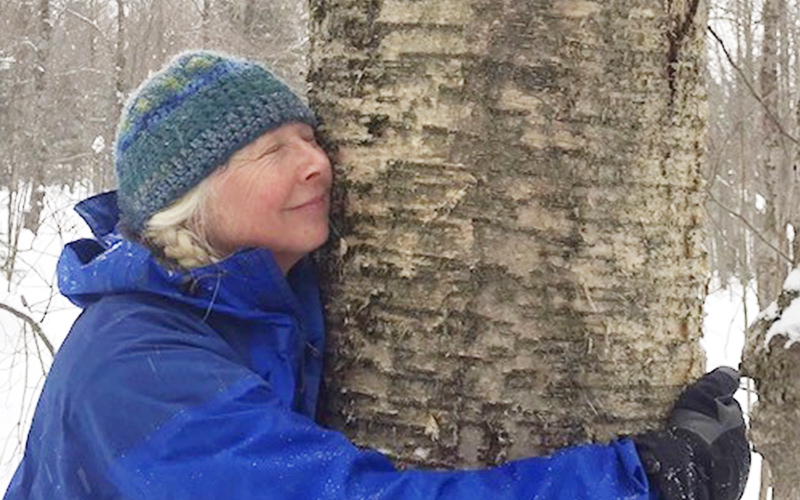2)	Marge Keough hugs a tree with chaga mushroom growing on its bark. Photo credit: Marge Keough 